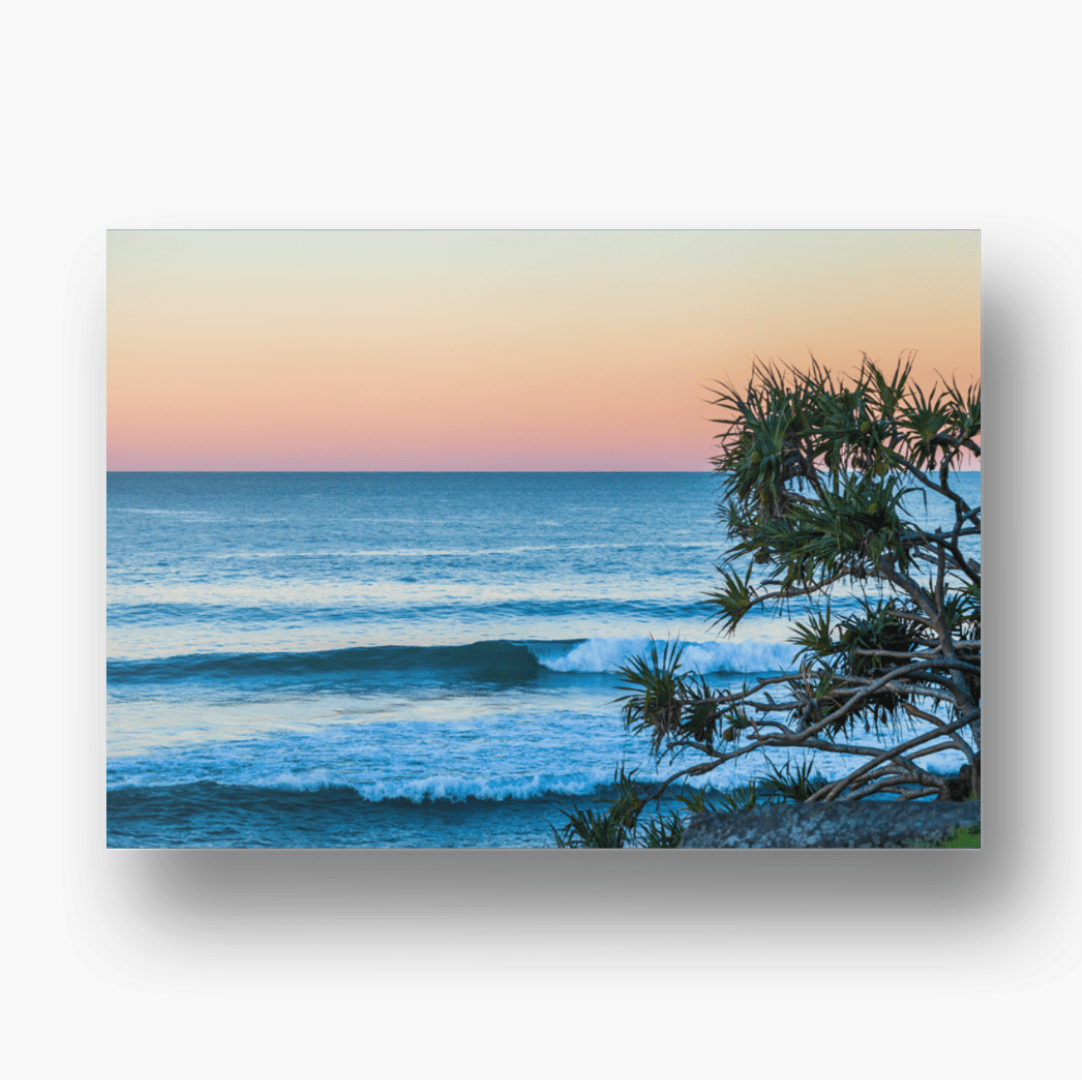 Sunrise over Burleigh Heads beach in Queensland, Australia, with soft pastel skies reflecting on calm ocean waves and golden sand in the foreground.