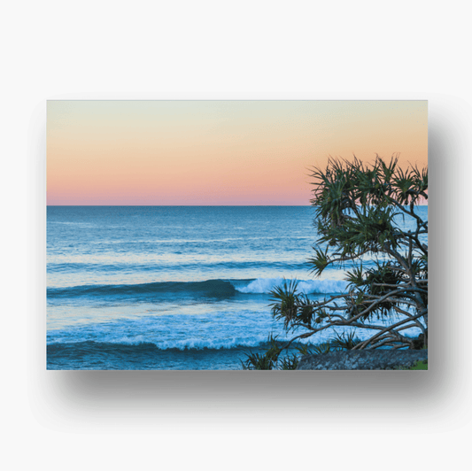 Sunrise over Burleigh Heads beach in Queensland, Australia, with soft pastel skies reflecting on calm ocean waves and golden sand in the foreground.