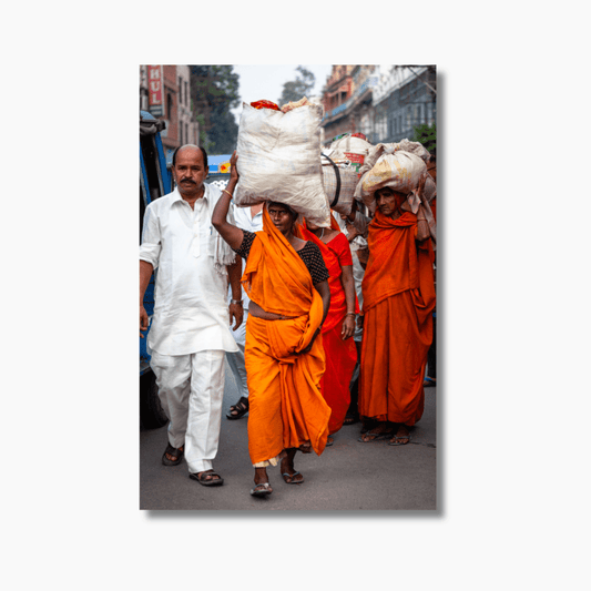 Women in orange garments carrying white sacks on their heads in Amritsar, India — limited edition cultural street photography wall art.