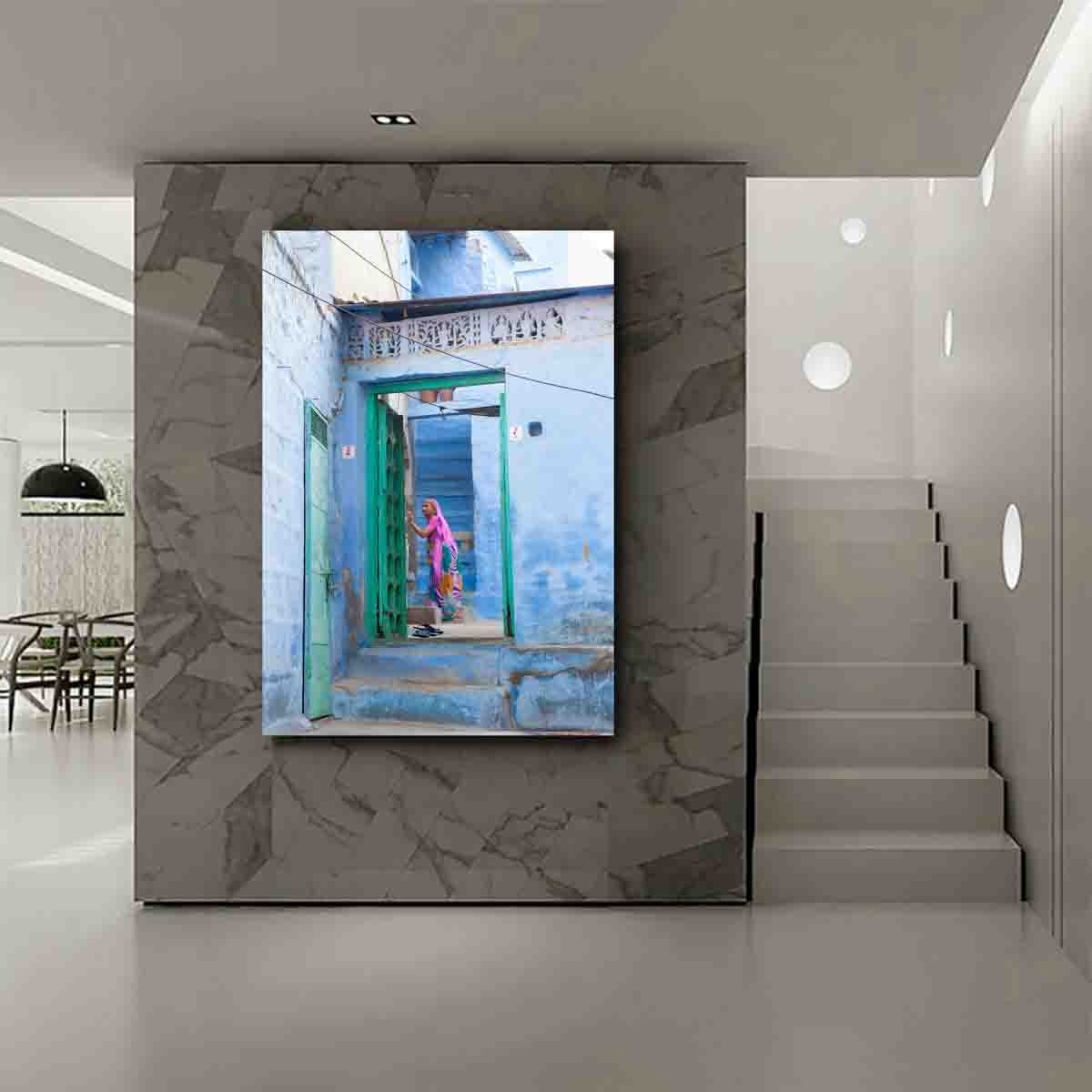Fine art wall print of a woman in soft purples walking through blue alleyways of Jodhpur, displayed in a serene, global-inspired interior.