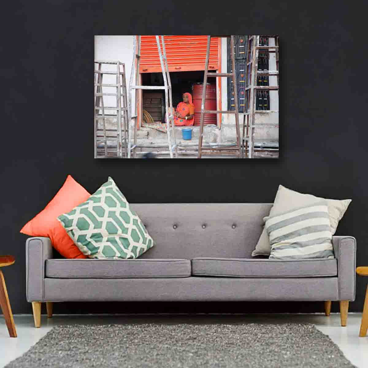 Fine art print of Indian woman in orange against a vivid backdrop in Jodhpur’s blue city, displayed in a contemporary global-inspired room.
