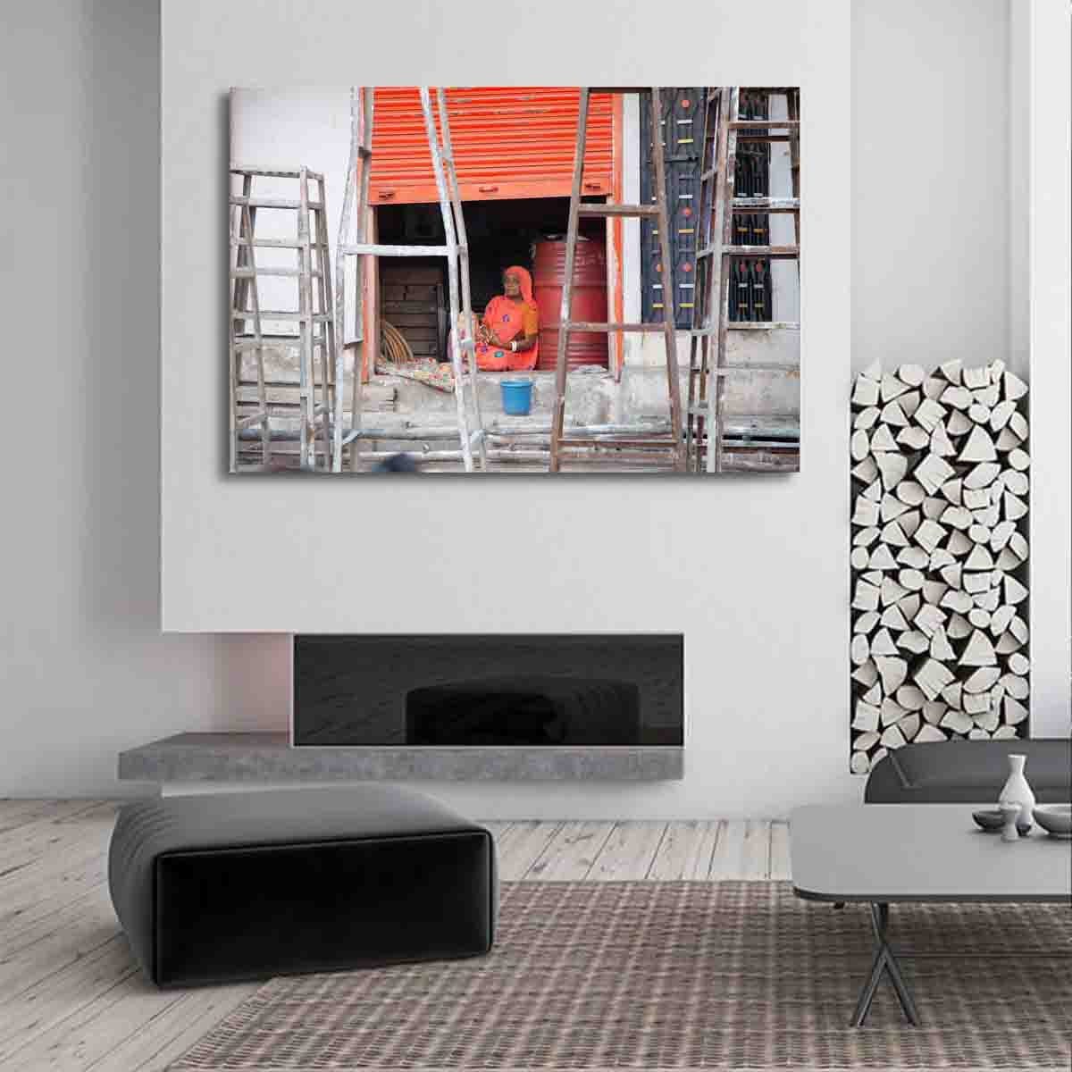 Fine art print of Indian woman in orange against a vivid backdrop in Jodhpur’s blue city, displayed in a contemporary global-inspired room.