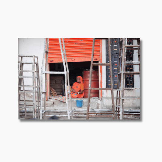 Woman in orange saree standing in front of orange roller door surrounded by scaffolding in Jodhpur, India — limited edition street photography print.