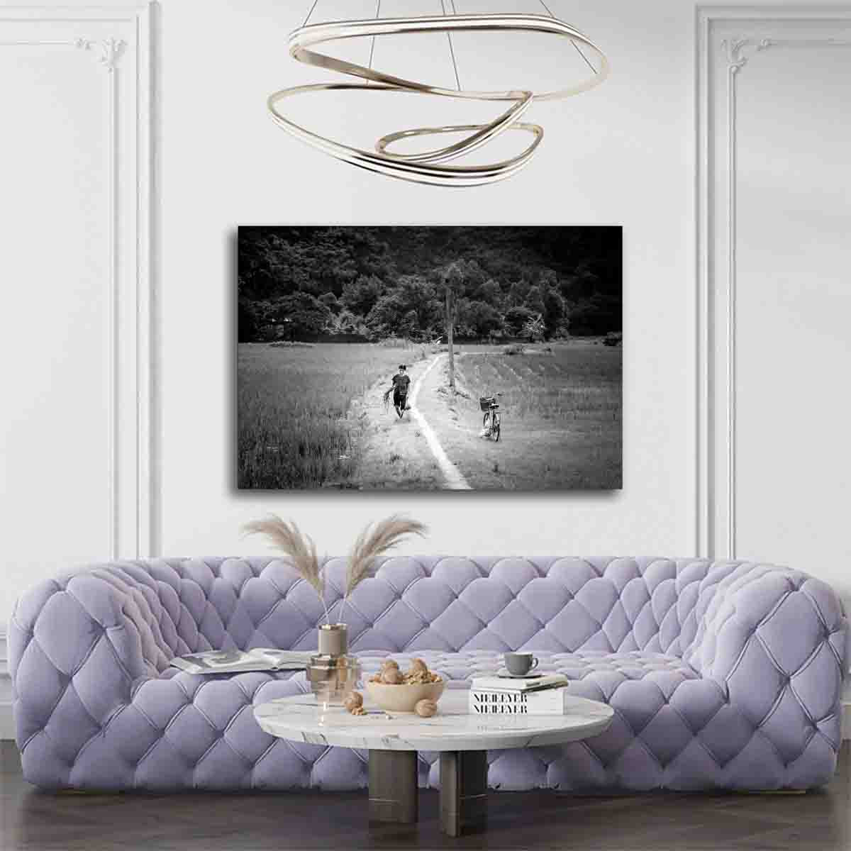 Vietnam rural wall art print showing a woman walking through fields in Ninh Binh, displayed in a calm, natural-toned interior.