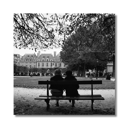 Couple sitting beneath trees looking at Notre Dame Cathedral in Paris — limited edition romantic photography wall art print.