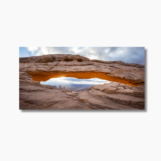 Sunrise through Mesa Arch in Canyonlands National Park, Moab, Utah, with glowing red rock and desert canyon view.