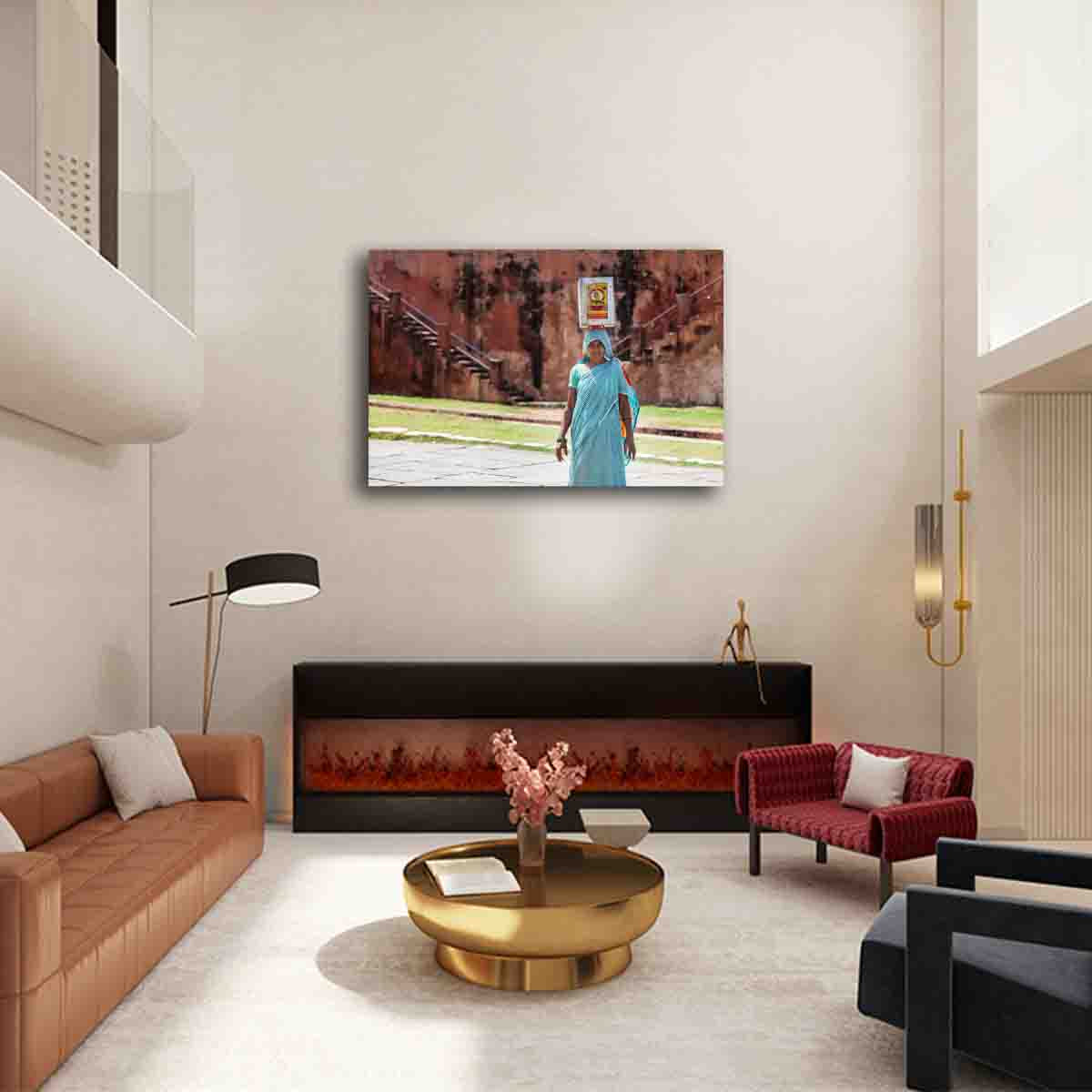 Cultural photography print of woman in India balancing container in turquoise saree, displayed as wall art in a modern global-inspired interior.