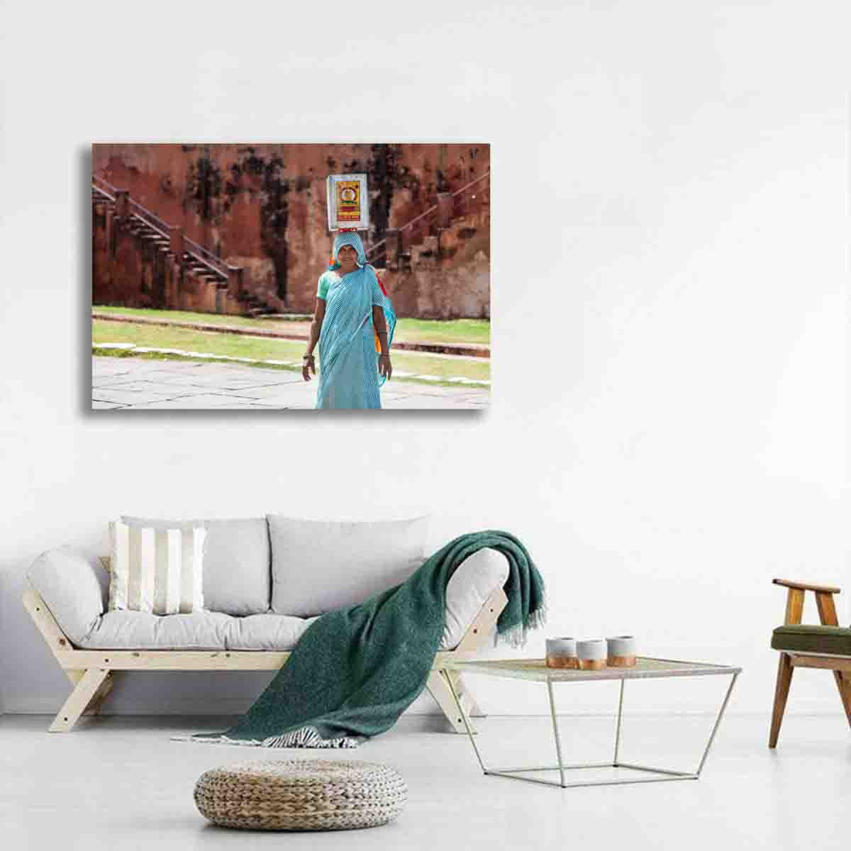 Cultural photography print of woman in India balancing container in turquoise saree, displayed as wall art in a modern global-inspired interior.