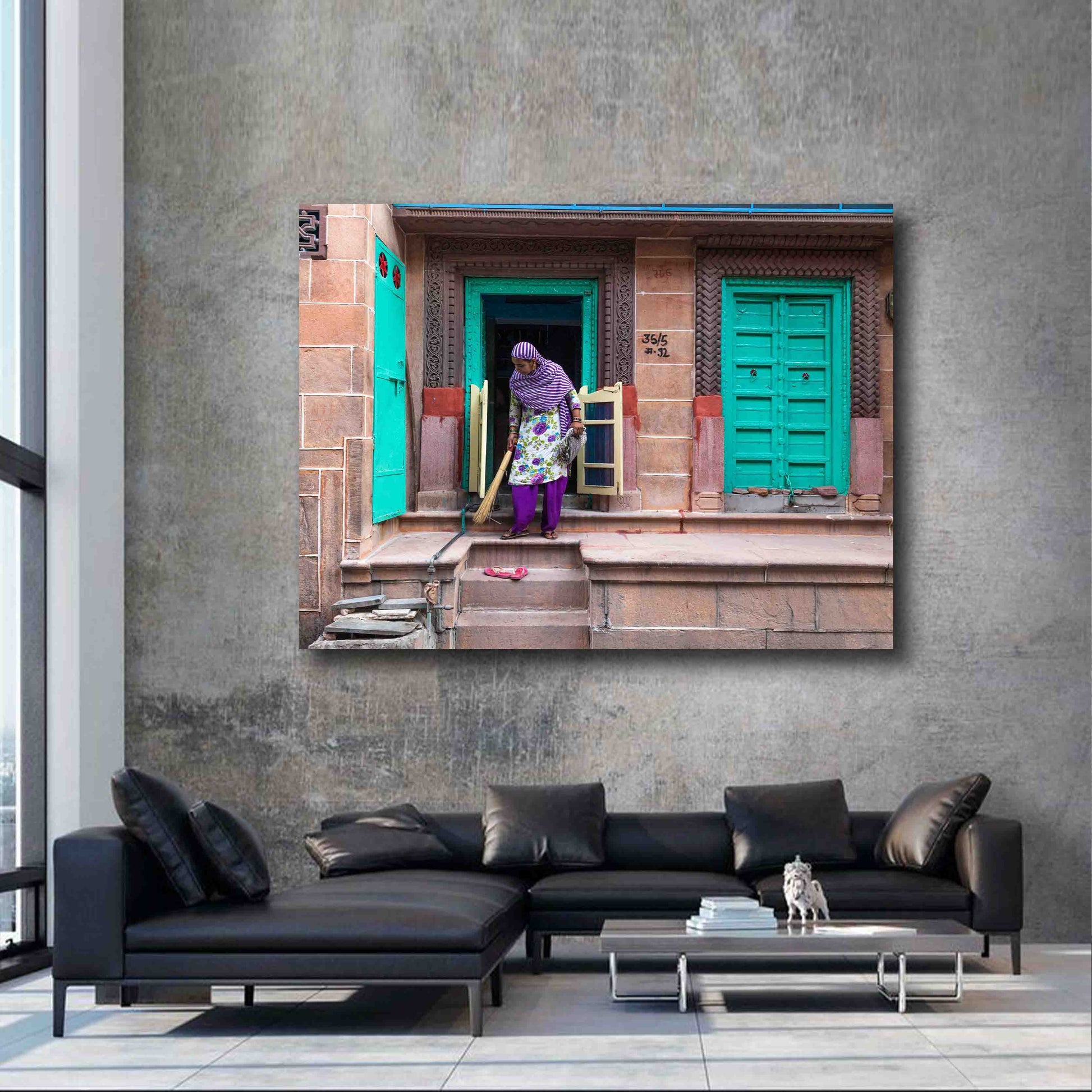 Street scene photograph of a woman sweeping in Jodhpur, displayed as limited edition fine art wall art in a warm, global-inspired interior.